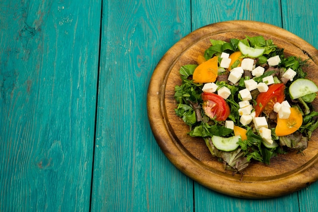 Insalata di verdure fresche con formaggio verde cetriolo pomodori su un tavolo di legno blu