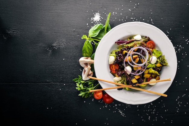 Insalata di verdure grigliate Funghi Feta e olio d'oliva Su una superficie di legno nera Spazio libero per il testo Vista dall'alto