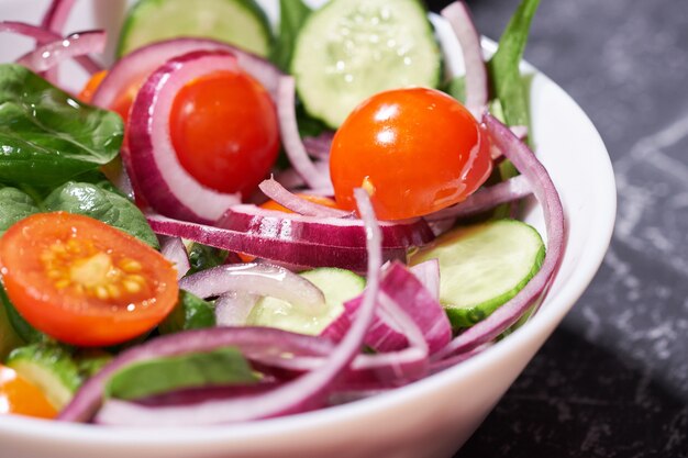 Insalata di verdure in un piatto bianco su uno sfondo grigio