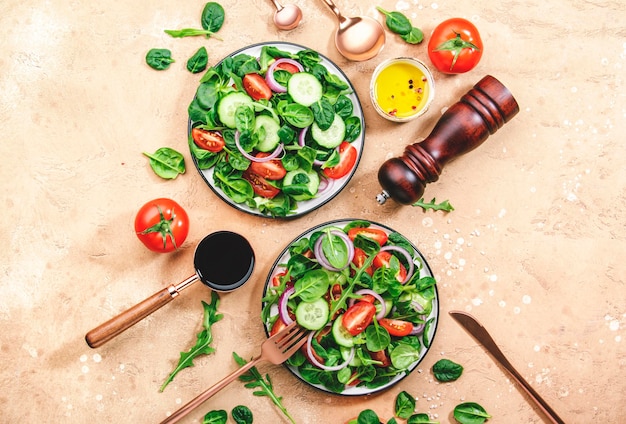 Insalata di verdure primaverili con spinaci verdi pomodori rossi cetriolo insalata di mais e cipolla Cibo vegano sano Sfondo del tavolo da cucina in pietra Vista dall'alto