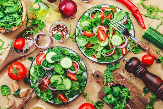 Insalata di verdure primaverili con spinaci verdi pomodori rossi cetriolo insalata di mais e cipolla Cibo vegano sano Sfondo del tavolo da cucina in pietra Vista dall'alto