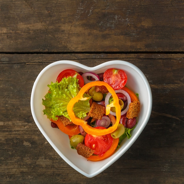 Insalata di verdure sana in un'insalatiera su un tavolo di legno.