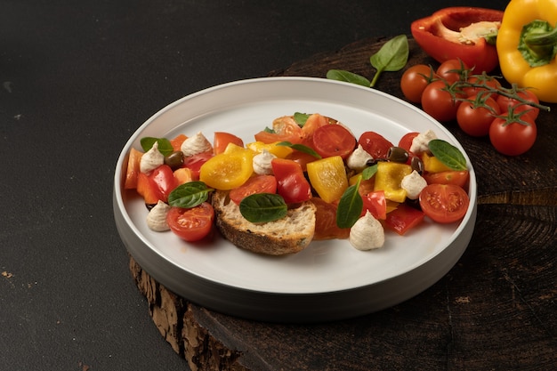 Insalata di verdure vegane con peperoni, pomodorini, basilico, capperi, pomodori secchi con pane bianco e salsa di arachidi