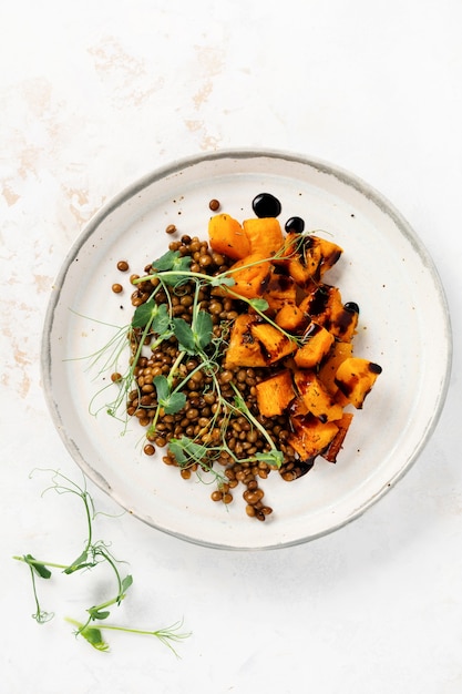 Insalata di zucca al forno, lenticchie e condimento balsamico guarnita con microgreens di piselli