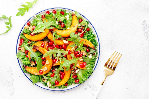 Insalata di zucca autunnale con miele al forno fette di zucca lattuga rucola semi di melograno e noci Cibo vegano sano Vista dall'alto