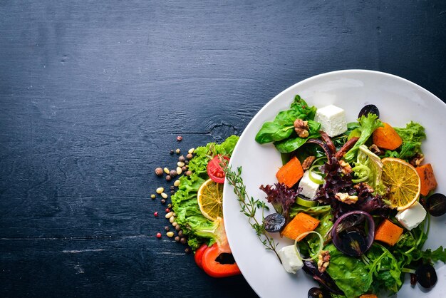 Insalata di zucca e verdure fresche. Cucina italiana. Vista dall'alto. Spazio libero per il testo. Su uno sfondo di legno.