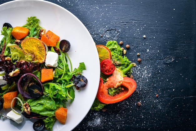 Insalata di zucca e verdure fresche. Cucina italiana. Vista dall'alto. Spazio libero per il testo. Su uno sfondo di legno.