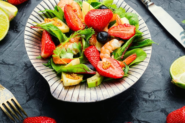 Insalata dietetica con gamberi, fragole e avocado. Insalata in un elegante piatto di metallo