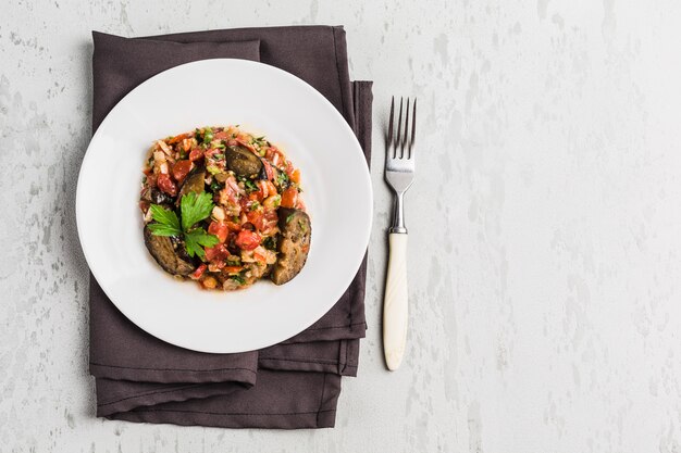 Insalata estiva di melanzane e pomodoro su un piatto bianco