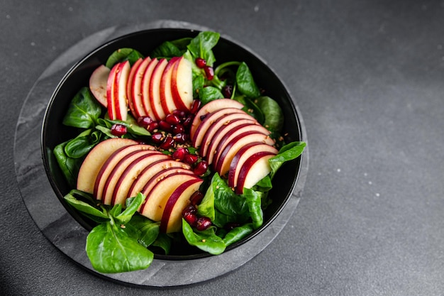 insalata fetta di mela mix verde lattuga chicco di melograno pasto sano spuntino sul tavolo