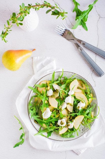 Insalata fresca con pere, rucola, ricotta e semi di zucca su un piatto Vista dall'alto e verticale