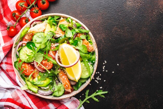 Insalata fresca con pollo pomodori rucola cipolla avocado semi di sesamo e olio di limone condimento Cibo sano Vista dall'alto Tavolo marrone