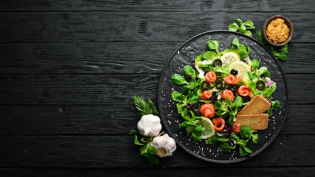 Insalata fresca con salmone e olive in lamiera nera Vista dall'alto Spazio libero per il testo Stile rustico