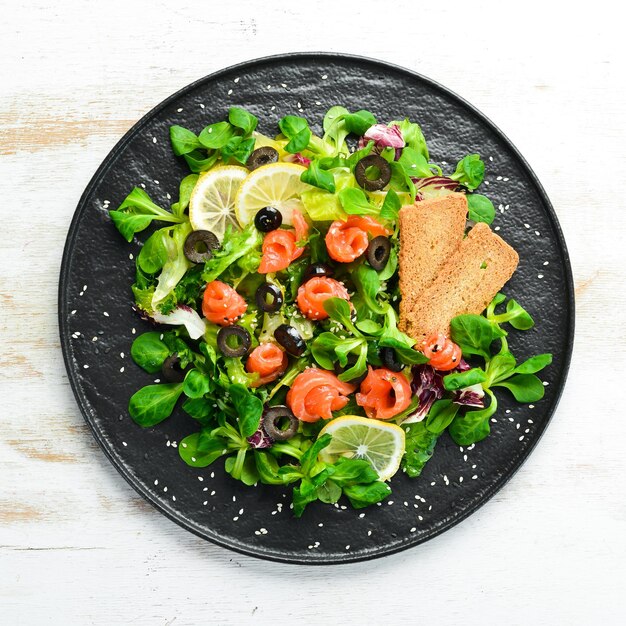 Insalata fresca con salmone e olive in lamiera nera Vista dall'alto Spazio libero per il testo Stile rustico