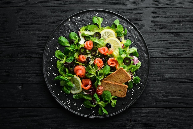 Insalata fresca con salmone e olive in lamiera nera Vista dall'alto Spazio libero per il testo Stile rustico