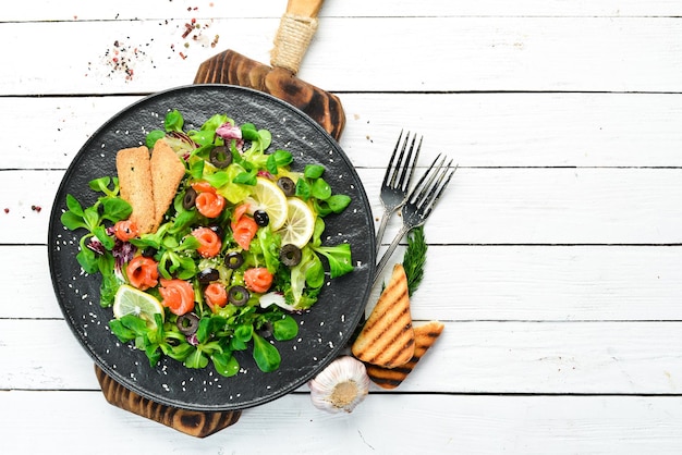 Insalata fresca con salmone e olive in piatto nero Vista superiore Spazio libero per il tuo testo Stile rustico