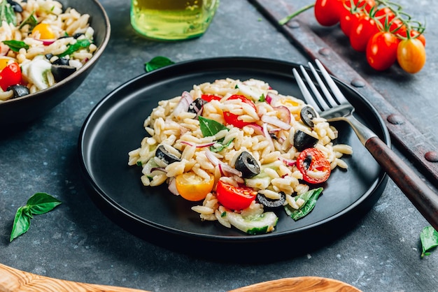 Insalata fresca di orzo estivo con olive nere, basilico, cipolla rossa, pomodoro e cetriolo