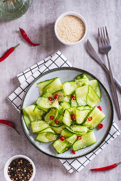 Insalata fresca di peperoncino piccante di cetrioli e semi di sesamo su una vista superiore e verticale del piatto