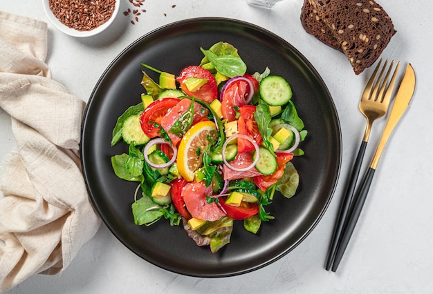 Insalata fresca e succosa con salmone, avocado e cetrioli condita con erbe fresche