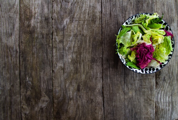 Insalata fresca in zolla sulla tavola di legno rustica. Spazio copia gratuita.