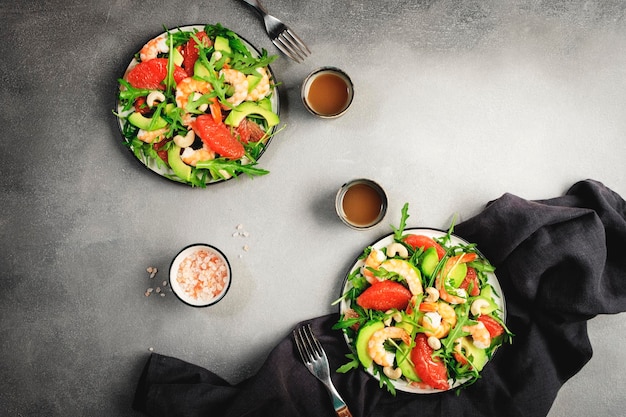 Insalata fresca sana con gamberetti avocado pompelmo rucola e anacardi Tavolo da cucina in pietra grigia sfondo vista dall'alto spazio copia