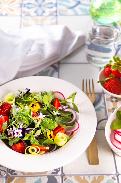 Insalata fresca sana primaverile con fiori commestibili verdi viole del pensiero viola e fragole