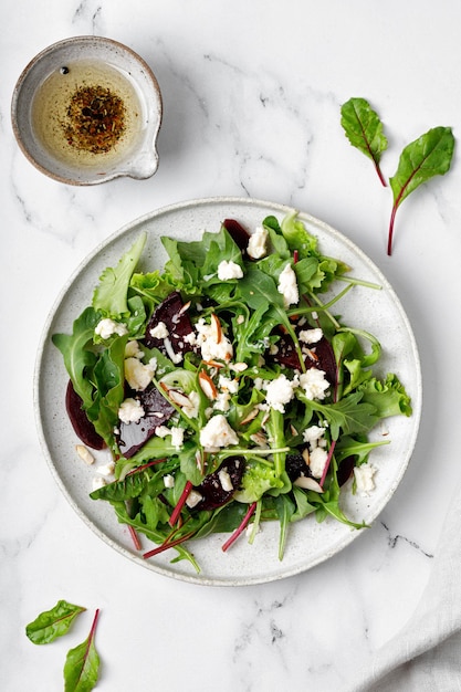 Insalata fresca verde con barbabietola o barbabietola verde mix lattuga dado feta formaggio su piastra in ceramica bianca olio