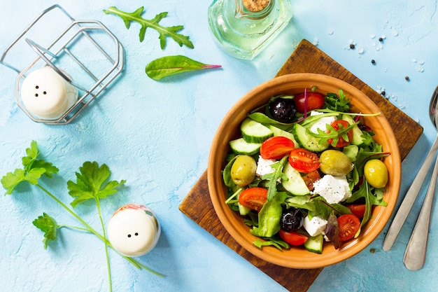 Insalata greca con feta di verdure fresche e olive nere su un tavolo di pietra blu o cemento