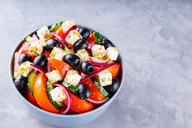 Insalata greca con feta e olive su sfondo grigio. Insalata mediterranea sana. Copia spazio. Vista dall'alto