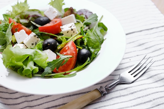 Insalata greca fresca in piatto bianco. Spazio per il testo.