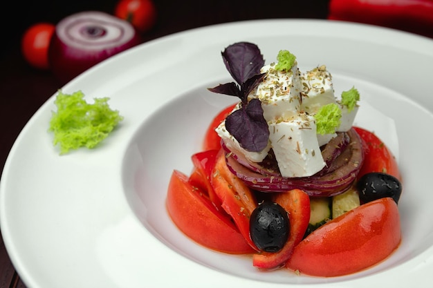 Insalata greca su un piatto su fondo scuro con messa a fuoco selettiva