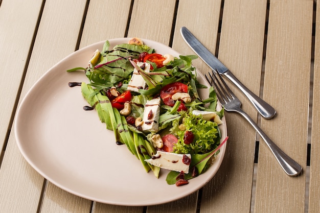 Insalata gustosa e salutare con rucola, brie, formaggio, avocado, pomodorini, mirtilli rossi secchi e anacardi.