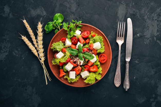 Insalata in un piatto Formaggio feta pomodorini lattuga alla paprika Cibo sano Sul tavolo di pietra Vista dall'alto Spazio libero per il testo