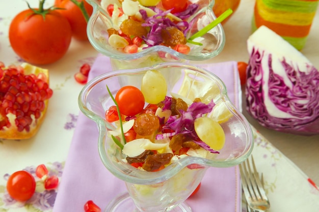 Insalata leggera e salutare in coppe da dessert: cavolo viola, chicchi di melograno, cipolla verde, uvetta, uva, foglie di insalata verde, pomodorini