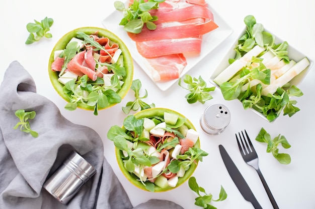 Insalata mediterranea estiva con prosciutto e melone su tavolo bianco