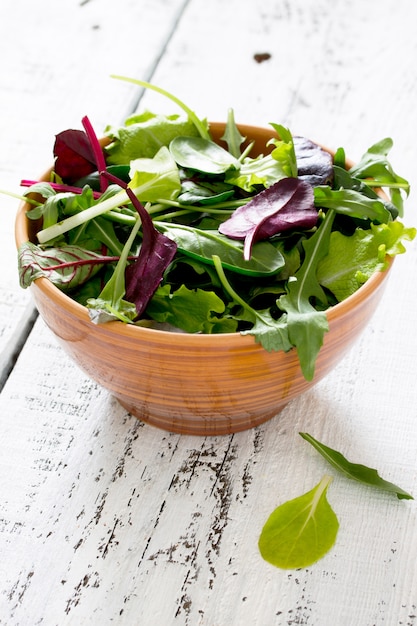 Insalata mista verde fresca in una ciotola su una tavola di legno