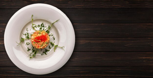 Insalata Olivier con caviale rosso su fondo in legno Banner