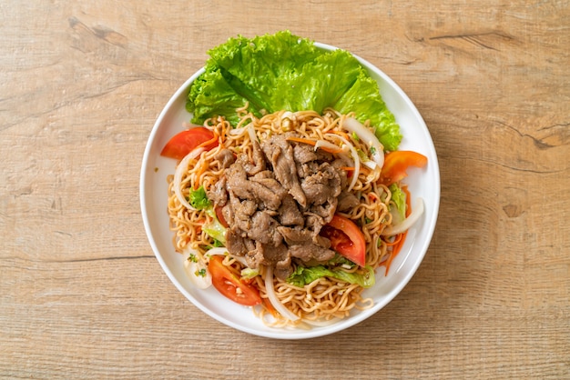 insalata piccante di noodle istantanei con carne di maiale sul piatto bianco - stile di cibo asiatico