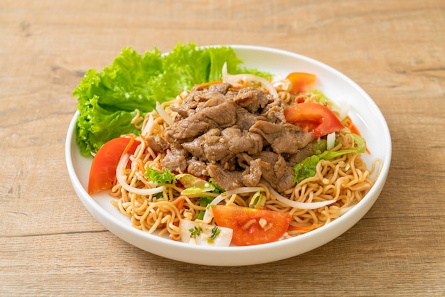 insalata piccante di spaghetti istantanei con carne di maiale sul piatto bianco - stile di cibo asiatico