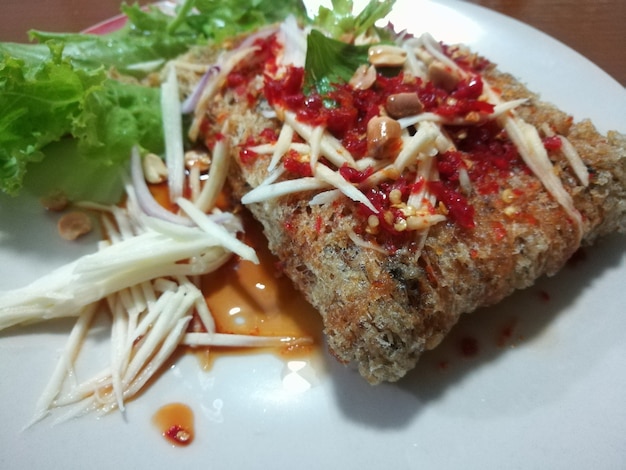 Insalata piccante Pesce gatto croccante con fetta di mango cibo gustoso caldo