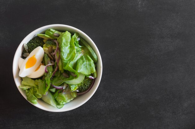 Insalata preparata con foglie verdi fresche, cipolla e uovo di gallina bollito