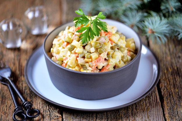 Insalata russa tradizionale Olivier su una vecchia superficie di legno. Cucina russa.