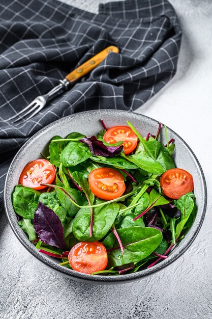 Insalata salutare con mix di foglie di mangold, bietola, spinaci e rucola in un'insalatiera. Sfondo bianco. Vista dall'alto.