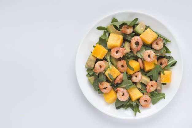 Insalata sana con avocado di frutta mango e gamberetti freschi su sfondo bianco Cibo sano