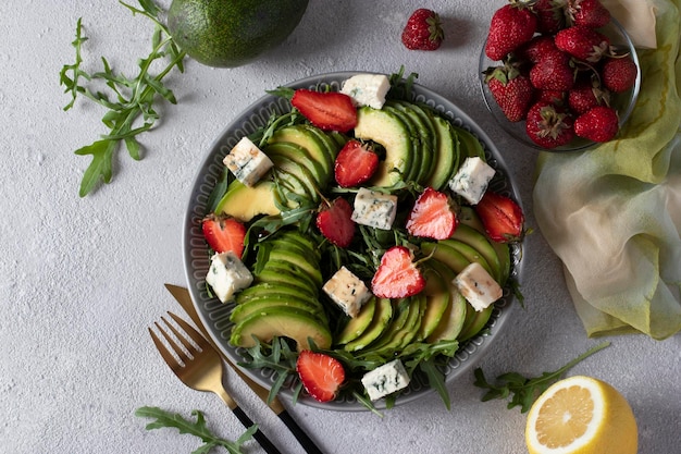 Insalata sana con fragole avocado rucola e formaggio dor blue condita con balsamico in un piatto