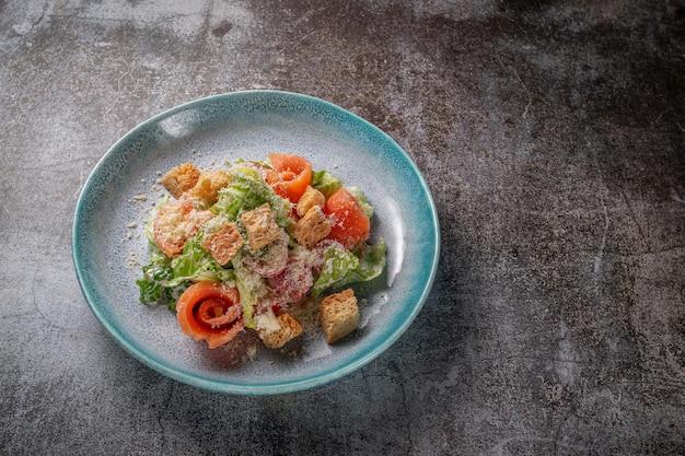 Insalata sana con verdure e salmone in un piatto contro un tavolo di pietra grigia