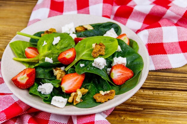 Insalata sana fresca con noci di spinaci alla fragola e formaggio feta sulla tavola di legno