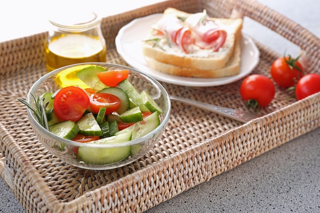 Insalata saporita e panino per colazione sul vassoio di vimini