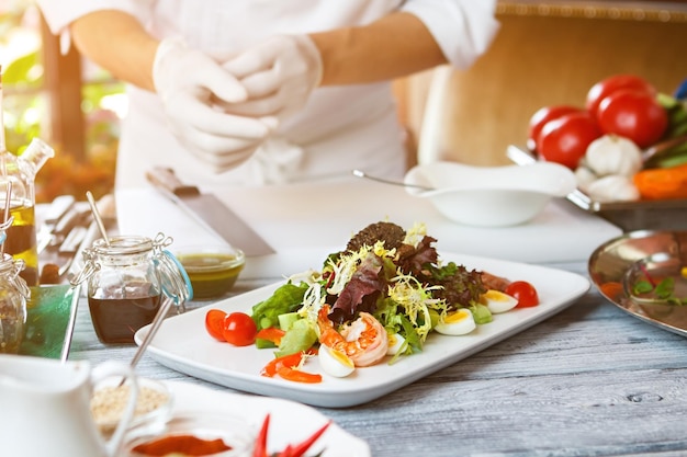 Insalata su piatto bianco. Uomo in piedi vicino al piatto di insalata. Tapenade di acciughe e uova di quaglia. Cucina europea al ristorante.