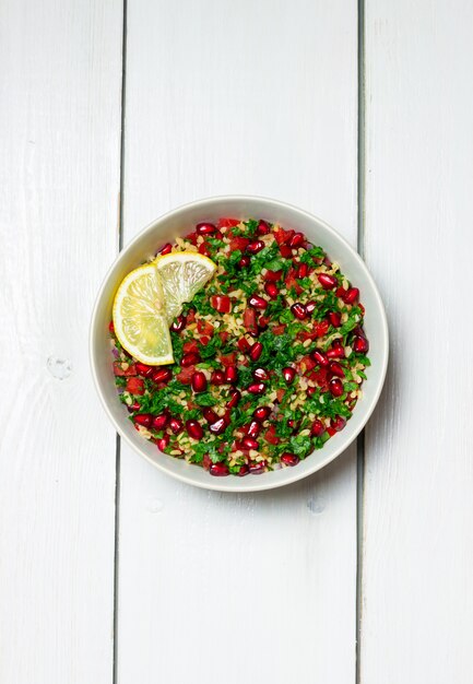 Insalata tabbouleh con bulgur, menta, prezzemolo, pomodori e melograno. Mangiare sano. Cibo vegetariano.